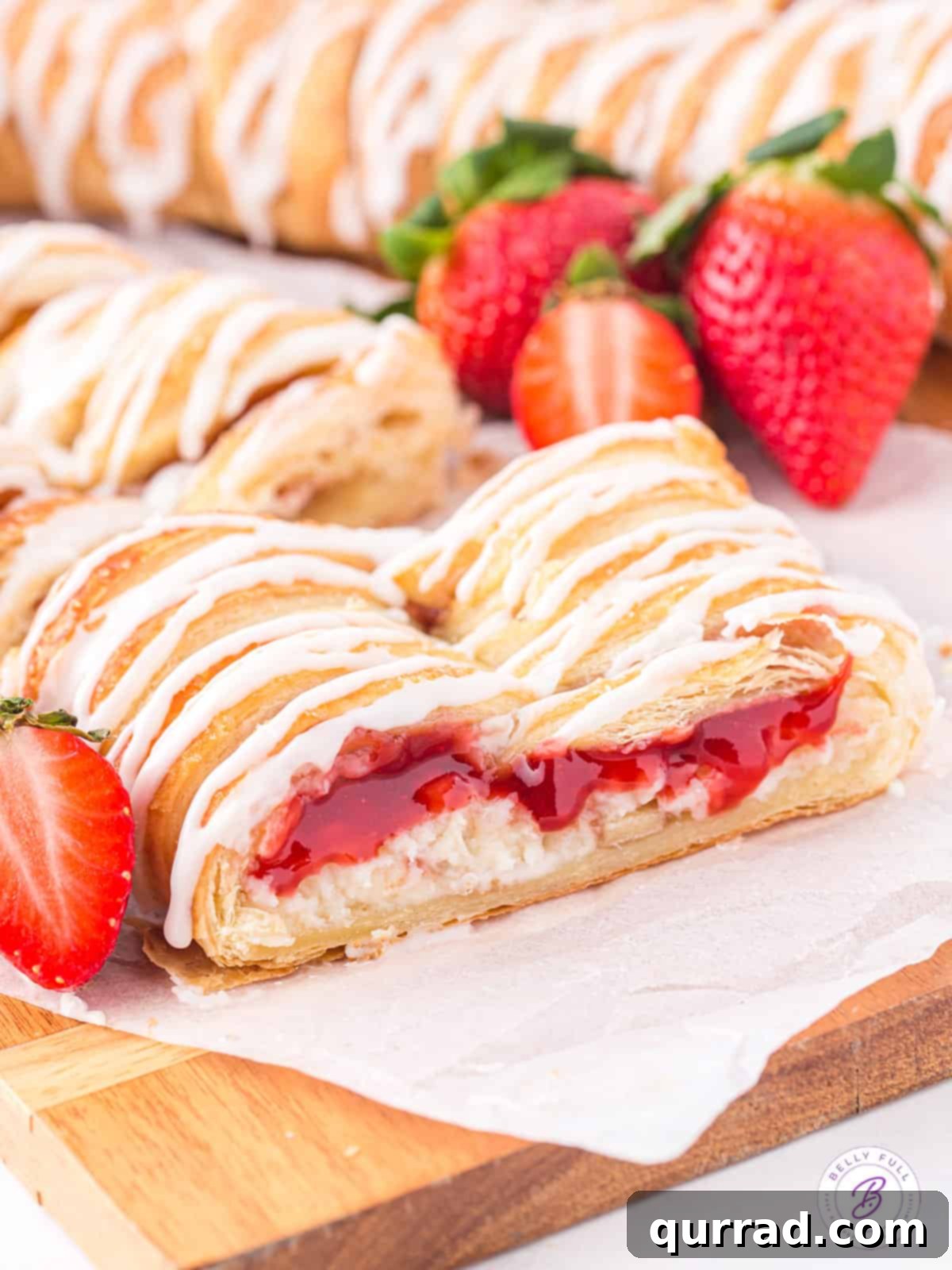 Angled view of a slice of strawberry cream cheese danish, showcasing its flaky layers and vibrant strawberry filling.