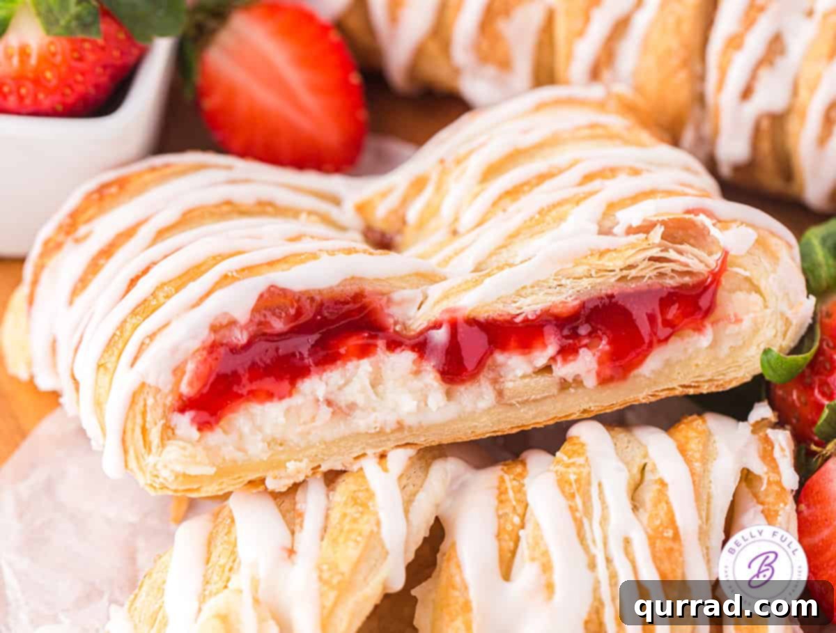 A perfectly sliced piece of strawberry danish resting on another slice, highlighting the layers of pastry, cream cheese, and strawberry filling.
