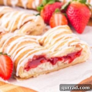 Angled view of a slice of strawberry cream cheese danish, showing the glazed top and rich filling.