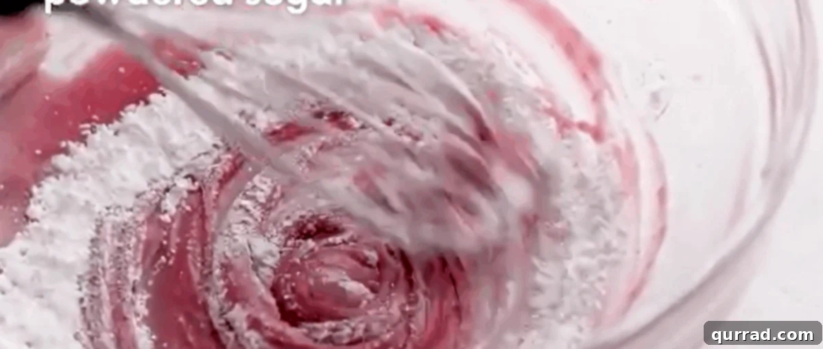 Ruby Raspberry Kisses 8 Whisking cream cheese, raspberry jam, and powdered sugar for a creamy macaron filling.