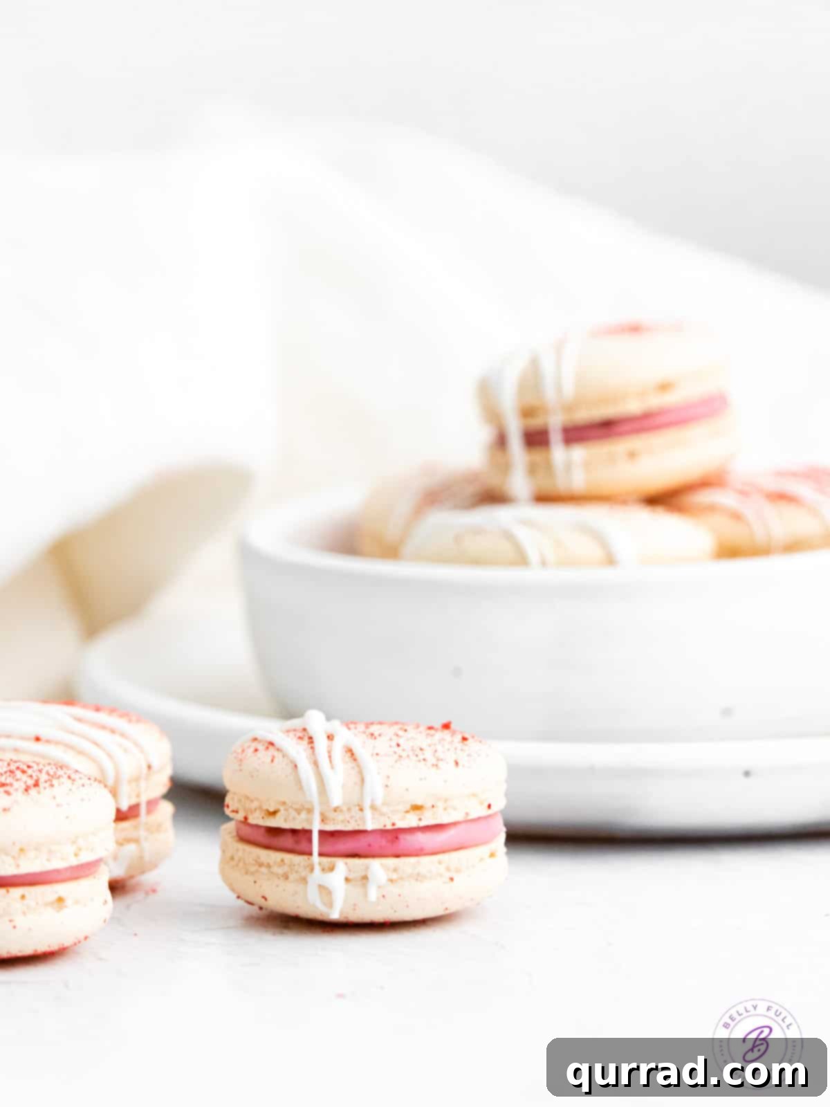 Delicate Raspberry Macarons: Master This 7-Ingredient French Cookie Recipe A perfectly assembled raspberry macaron with a bowl of finished macarons in the background.