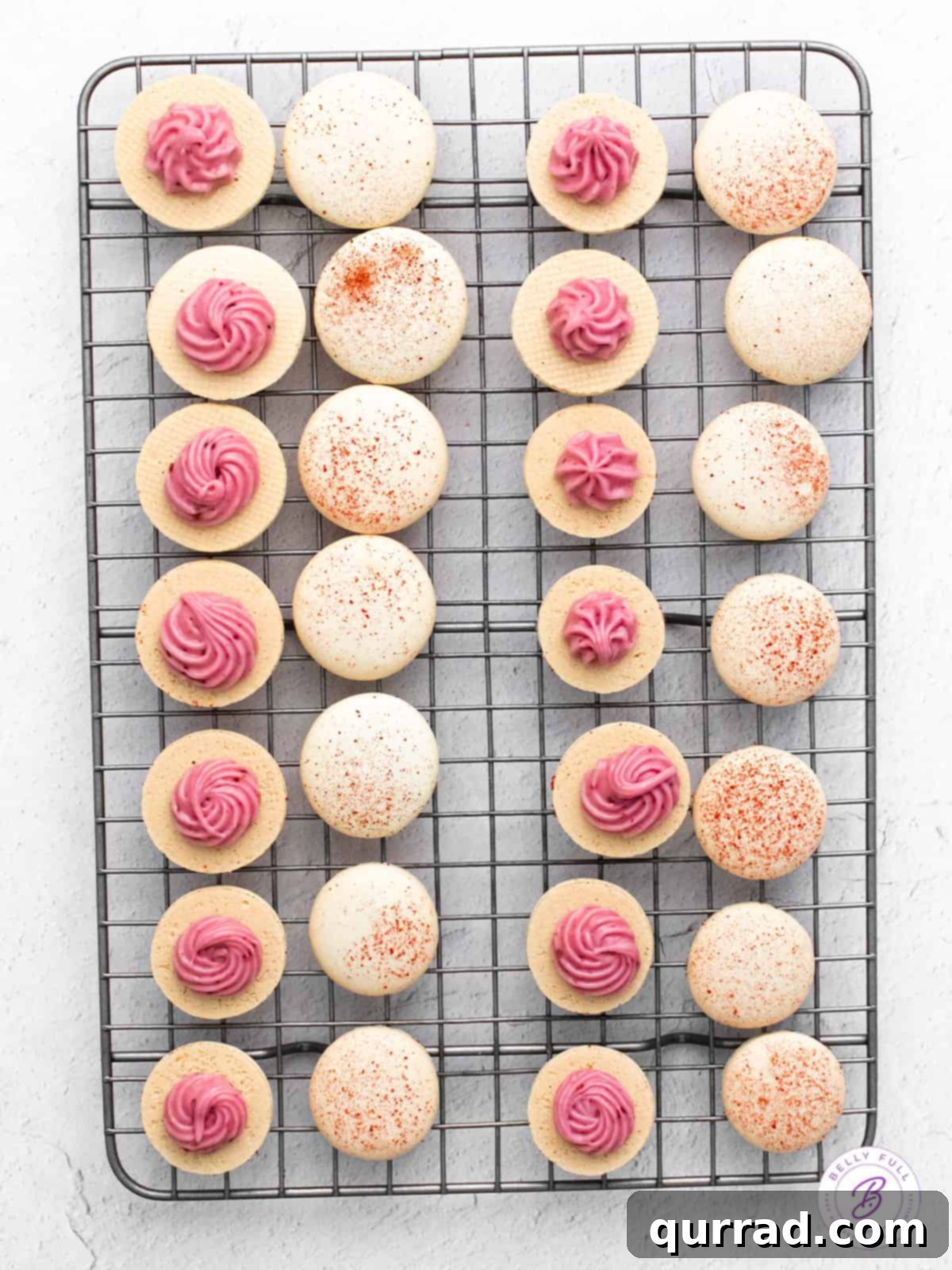 Homemade Raspberry Macarons: Simple Recipe for Elegant French Desserts Raspberry macarons cooling on a rack, some filled, some waiting for their creamy center.