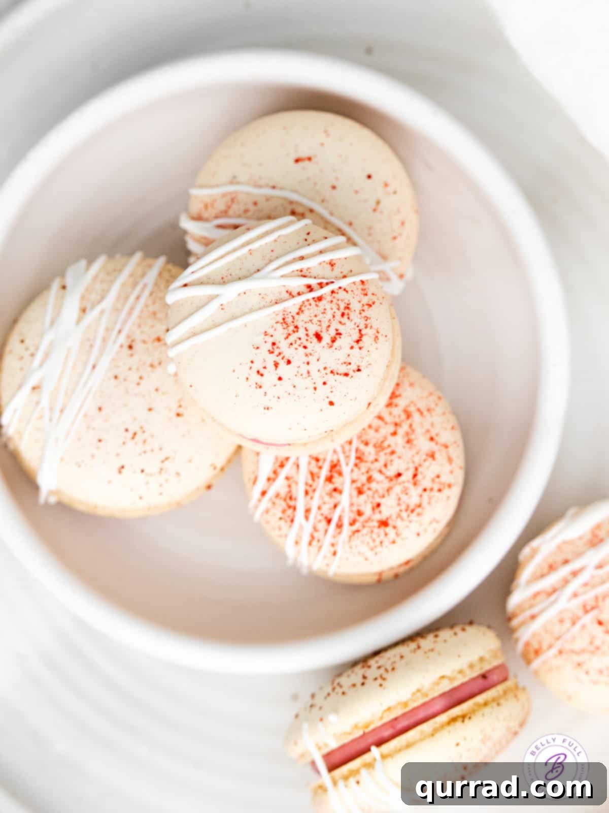 Indulge in Homemade Raspberry Macarons: Your Guide to French Patisserie Perfection Overhead view of perfectly arranged raspberry macarons in a white bowl, ready to be enjoyed.