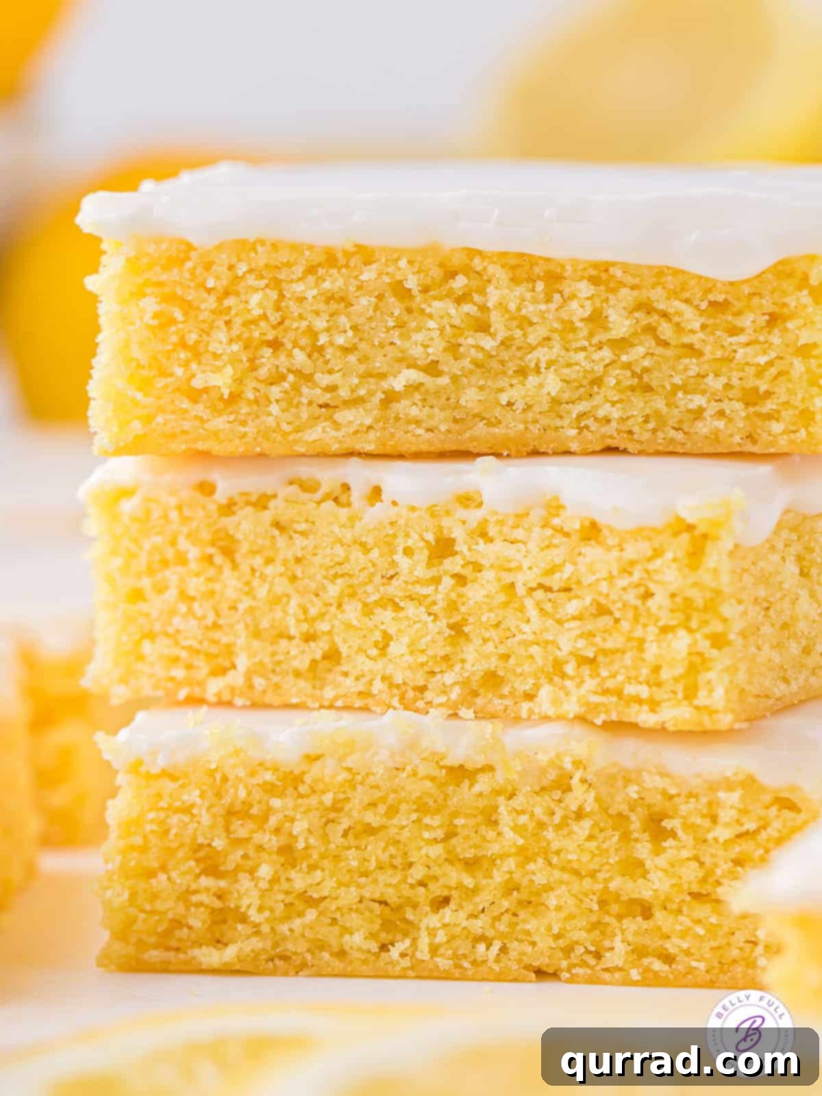 Soft and moist, these Lemon Blondies are the ultimate easy lemon dessert. Just 9 ingredients and a few steps to make! Three lemon blondies stacked on each other, showcasing their moist texture and bright glaze.