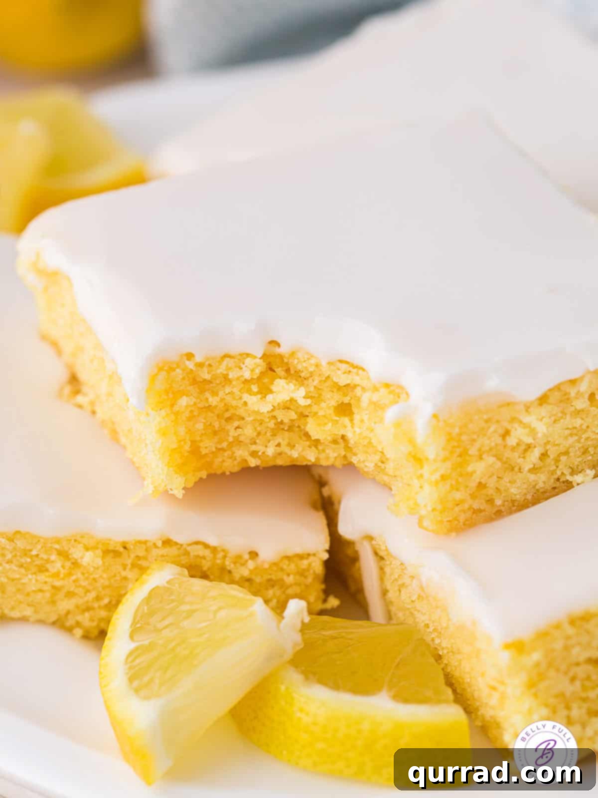 Soft and moist, these Lemon Blondies are the ultimate easy lemon dessert. Just 9 ingredients and a few steps to make! A single lemon blondie with a bite missing, showing its soft interior and glistening glaze.