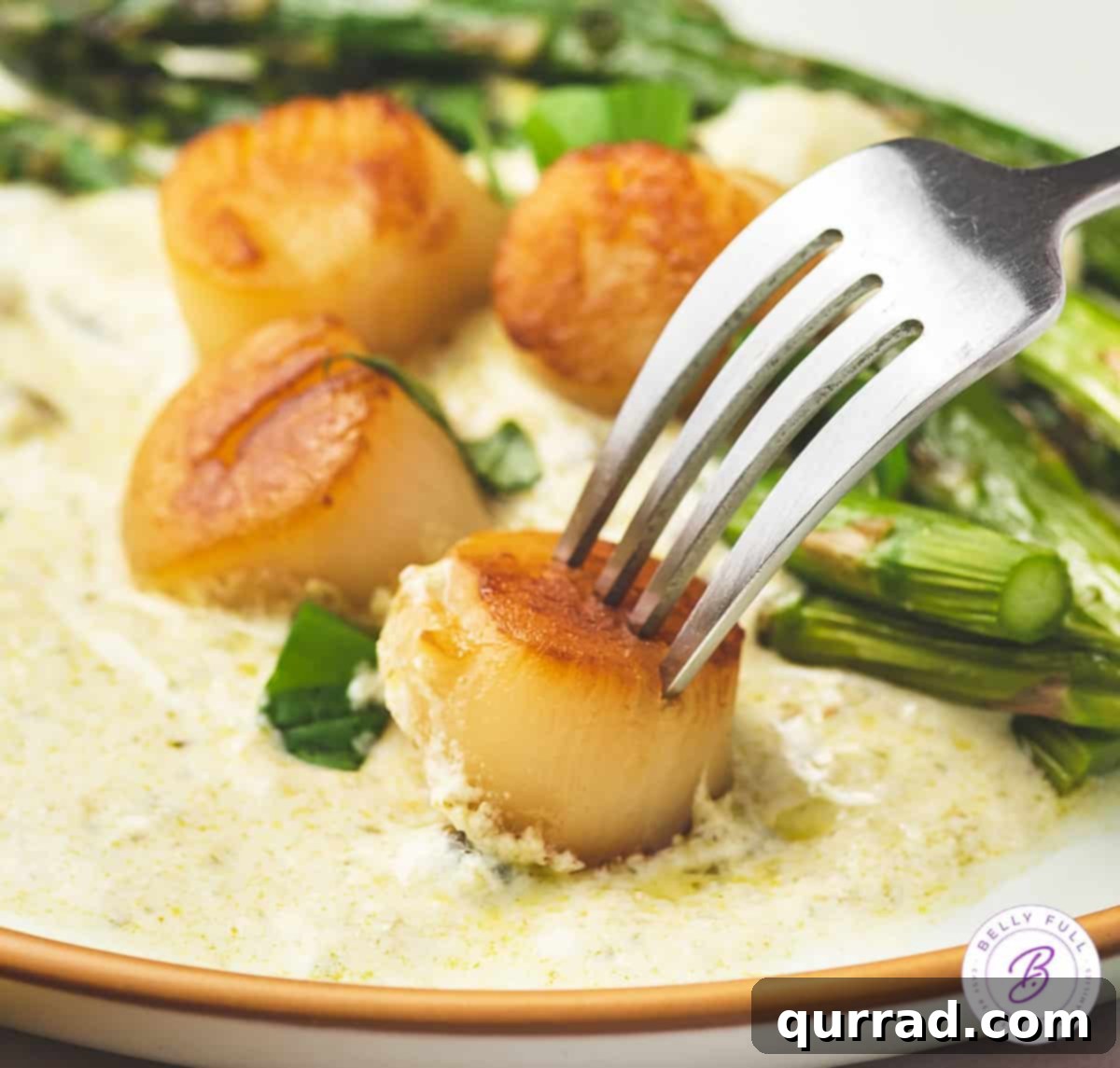A fork piercing a plump seared scallop, coated in pesto cream, showcasing the tender interior.