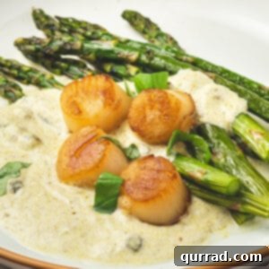 Angled view of a plate of scallops with pesto cream and asparagus