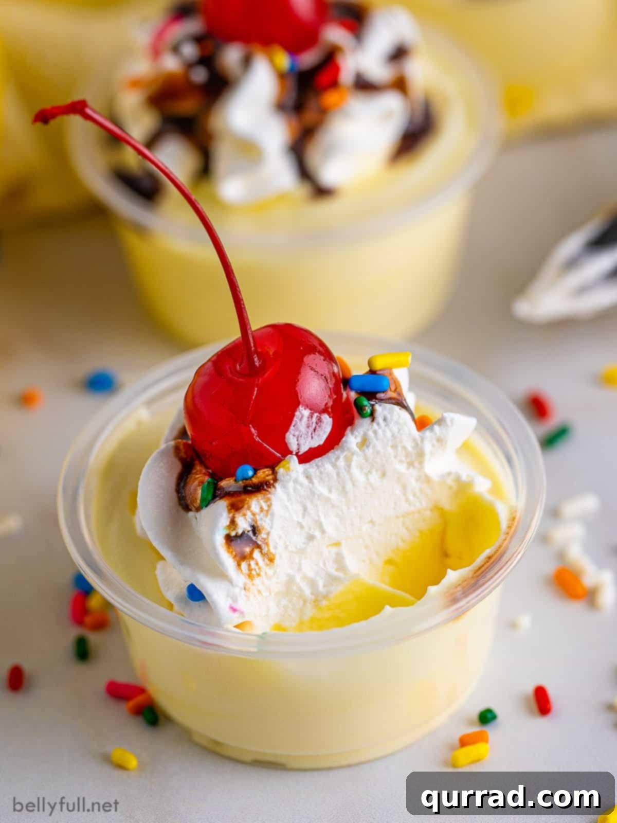 The irresistible texture of a banana split pudding shot. A close-up of a Banana Split Pudding Shot with a spoonful missing, revealing its creamy, mousse-like interior and inviting texture.