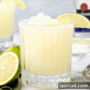 Side view of a frozen margarita in a glass garnished with a lime slice