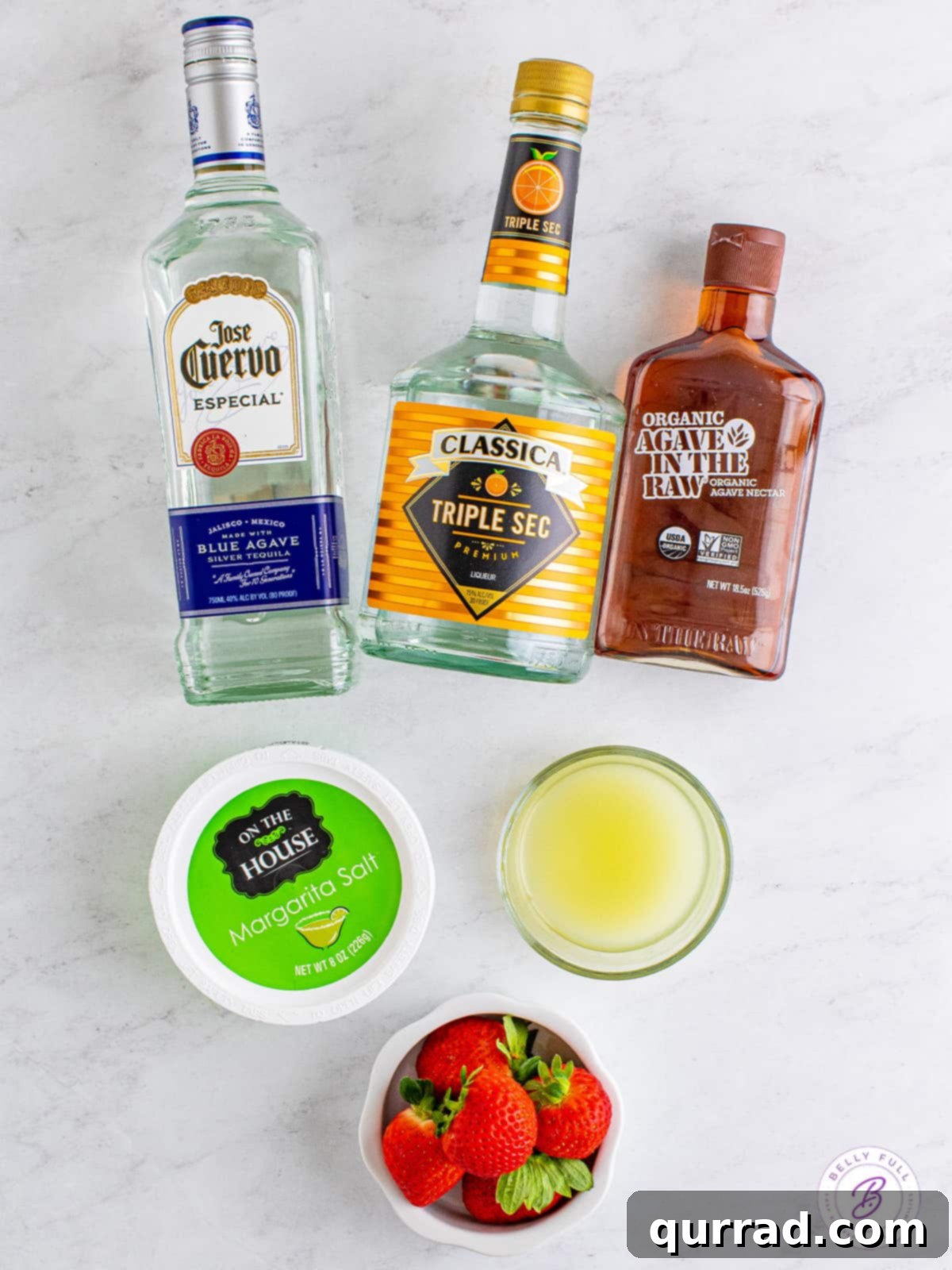 Refreshing, sweet, and tart this Strawberry Margarita is made with just 6 ingredients, with no margarita mix. Perfect for parties! Overhead view of fresh strawberry margarita ingredients laid out on a table, including strawberries, lime, tequila, and triple sec.