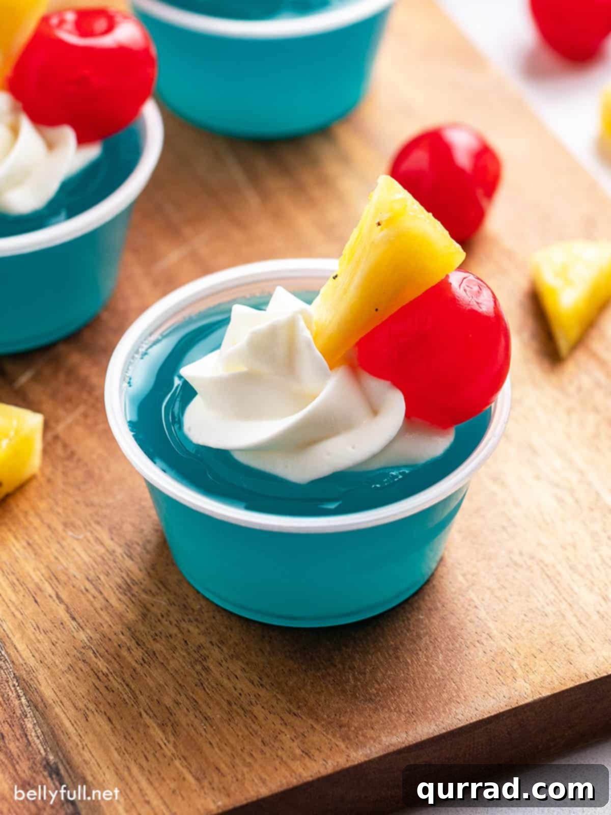 Blue Hawaiian jello shot garnished with pineapple and a maraschino cherry