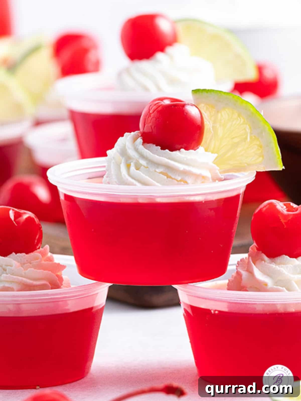 Dirty Shirley Temple Jello shot with whipped cream, cherry, and lime garnish