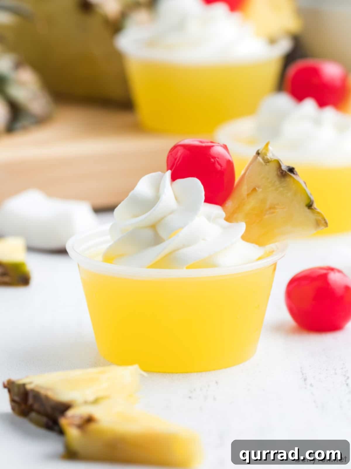 Pineapple Jello Shot with whipped cream, pineapple wedge, and maraschino cherry