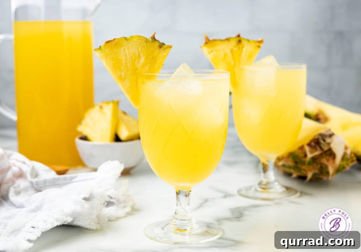 2 glasses of pineapple rum punch with pineapple wedge garnish