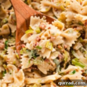 creamy bowtie pasta with pancetta and onion on wooden spoon