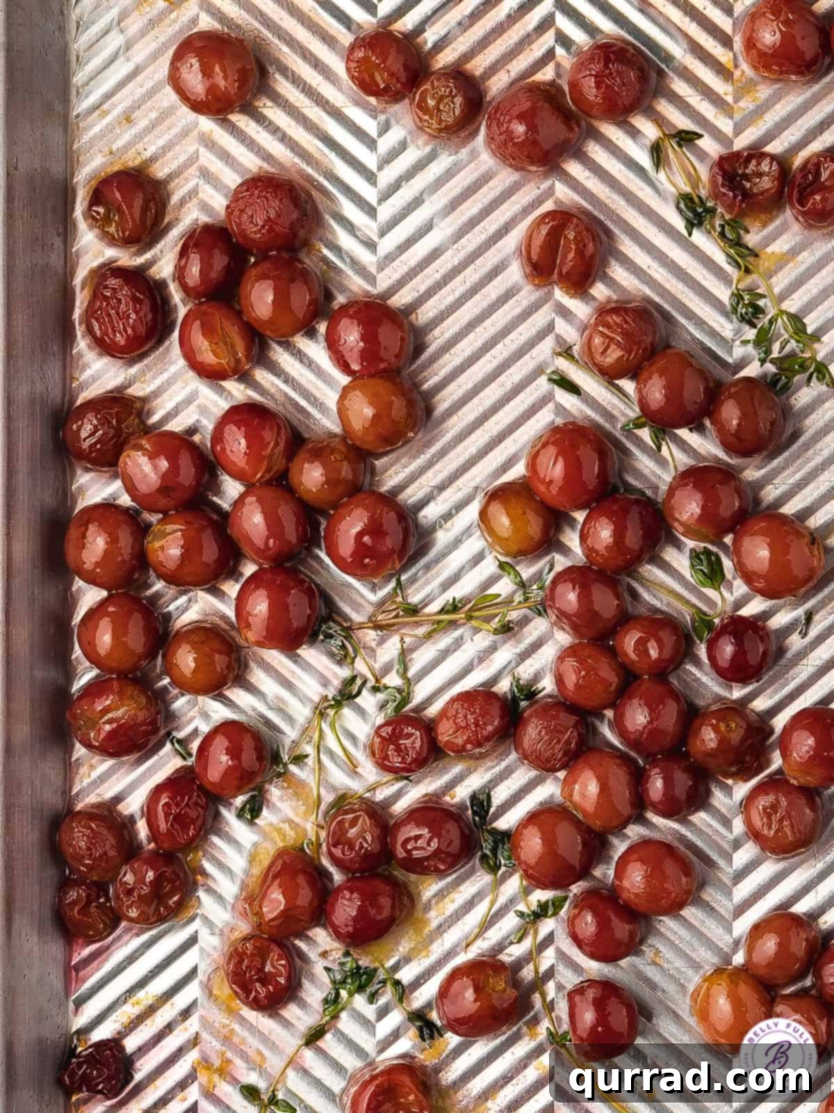 Oven Kissed Grapes 3 roasted red grapes with fresh thyme sprigs on baking sheet