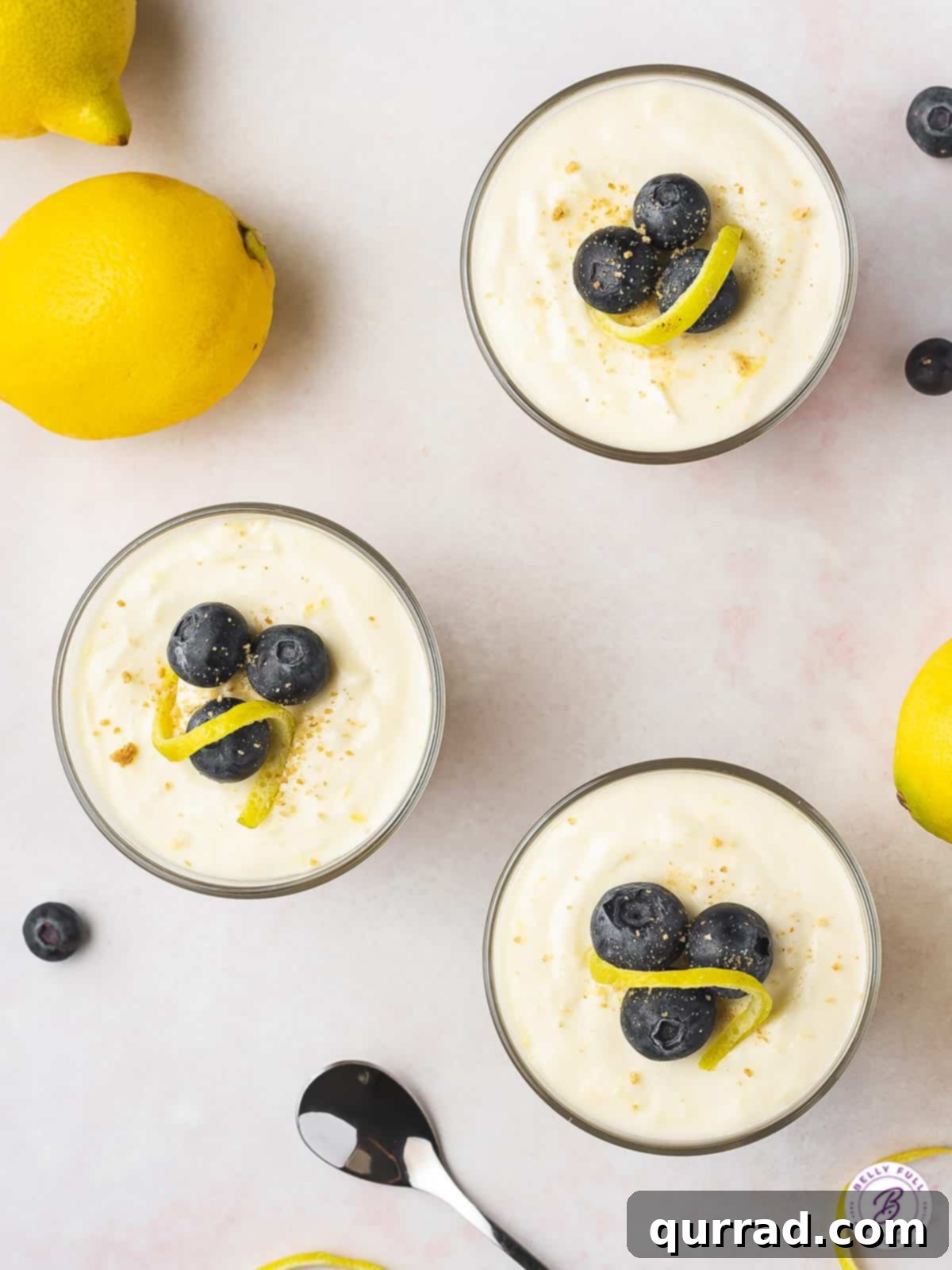 Indulge in the light and creamy texture of this Lemon Cheesecake Mousse, a delightful no-bake treat for spring and summer! Close-up overhead view of three lemon cheesecake mousses, showcasing their creamy texture and elegant garnishes.