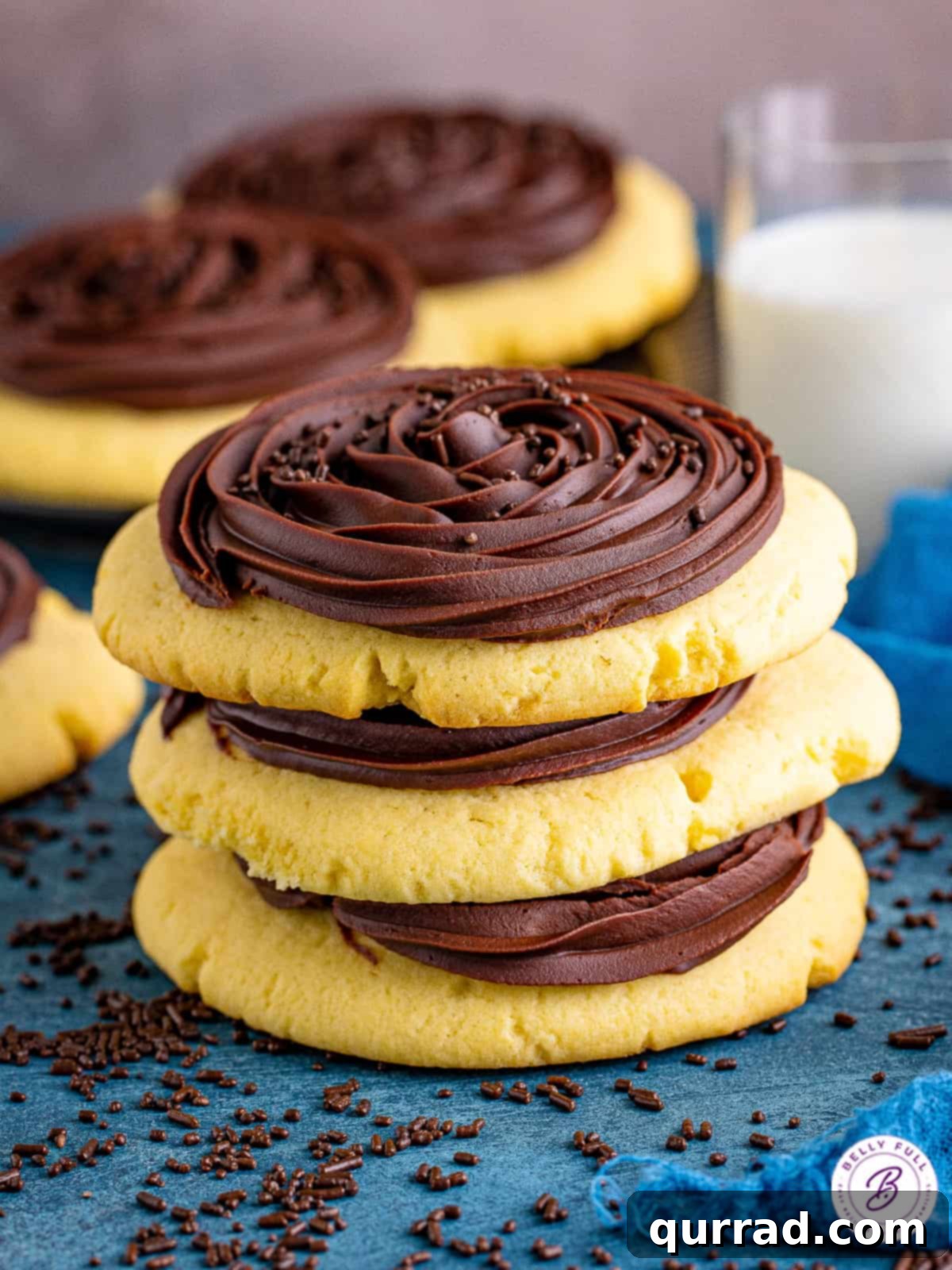 Three stacked Crumbl chocolate cupcake cookies, a feast for the eyes and taste buds. A stack of three Crumbl chocolate cupcake cookies, showing off the thick ganache and sprinkles.