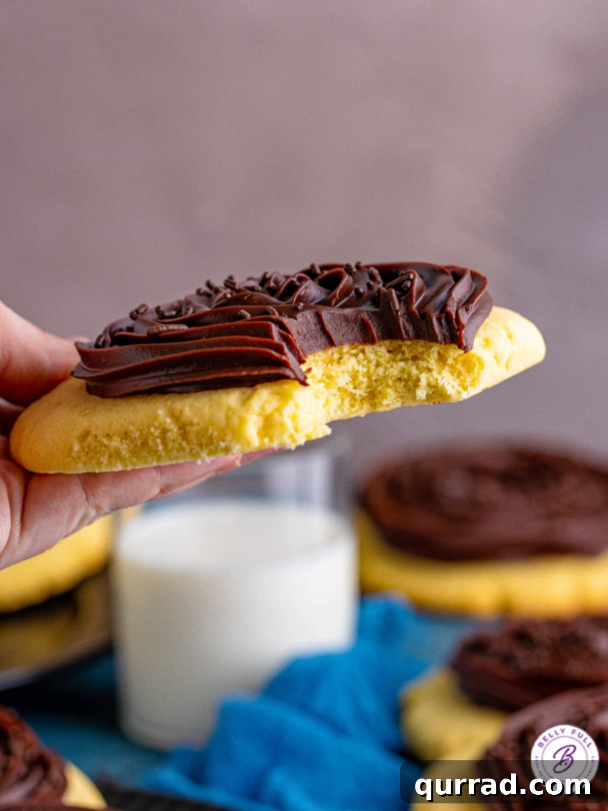 A delicious Crumbl chocolate cupcake cookie, showcasing its perfect texture. A hand holding a copycat Crumbl cookie with a bite taken out, revealing the soft interior.