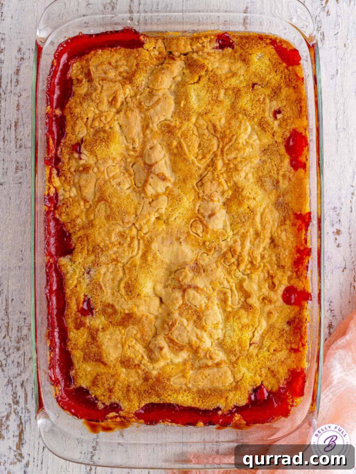 Cherry Dump Cake: A delightful and easy baked dessert An overhead view of a freshly baked cherry dump cake in a 9x13 inch baking dish, showing the bubbly fruit filling and golden brown cake topping.