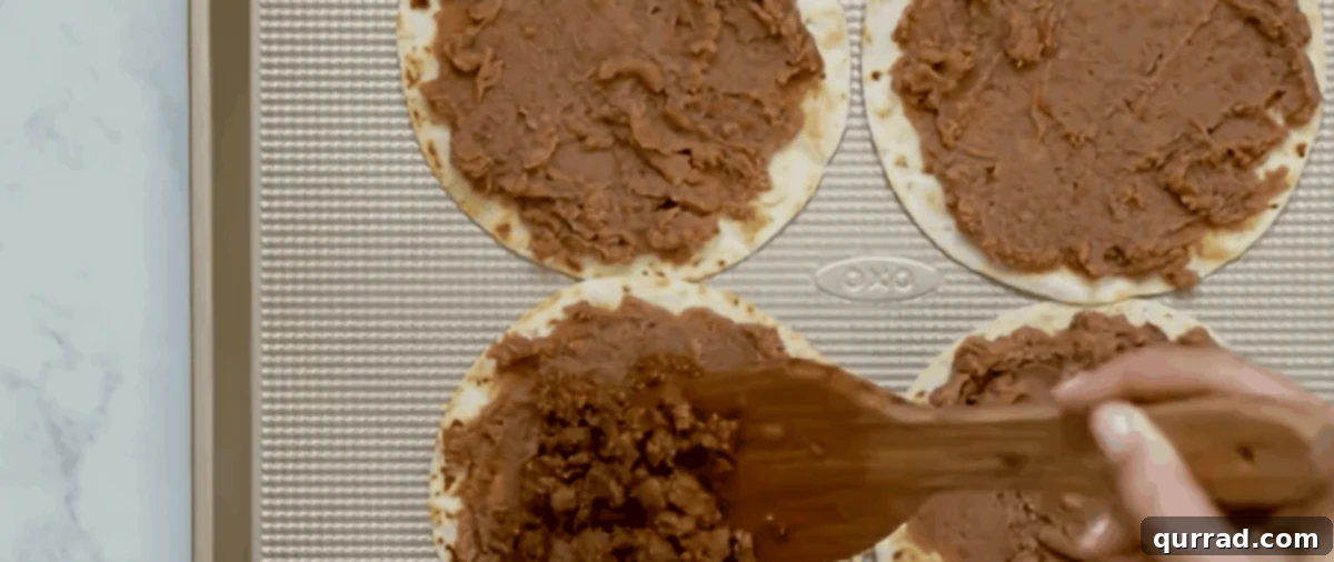 Layering beans and meat on tortillas.