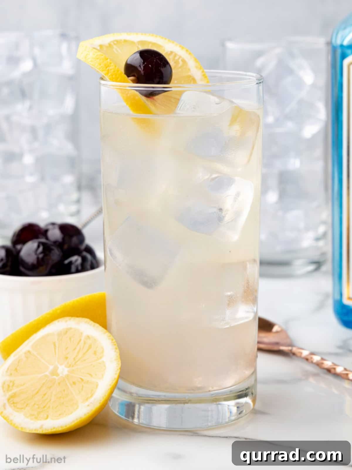 Classic Tom Collins Cocktail: A Smooth and Refreshing Gin Drink A tall, refreshing Tom Collins cocktail in a highball glass, garnished with a lemon slice and a vibrant red cherry, perfect for summer.