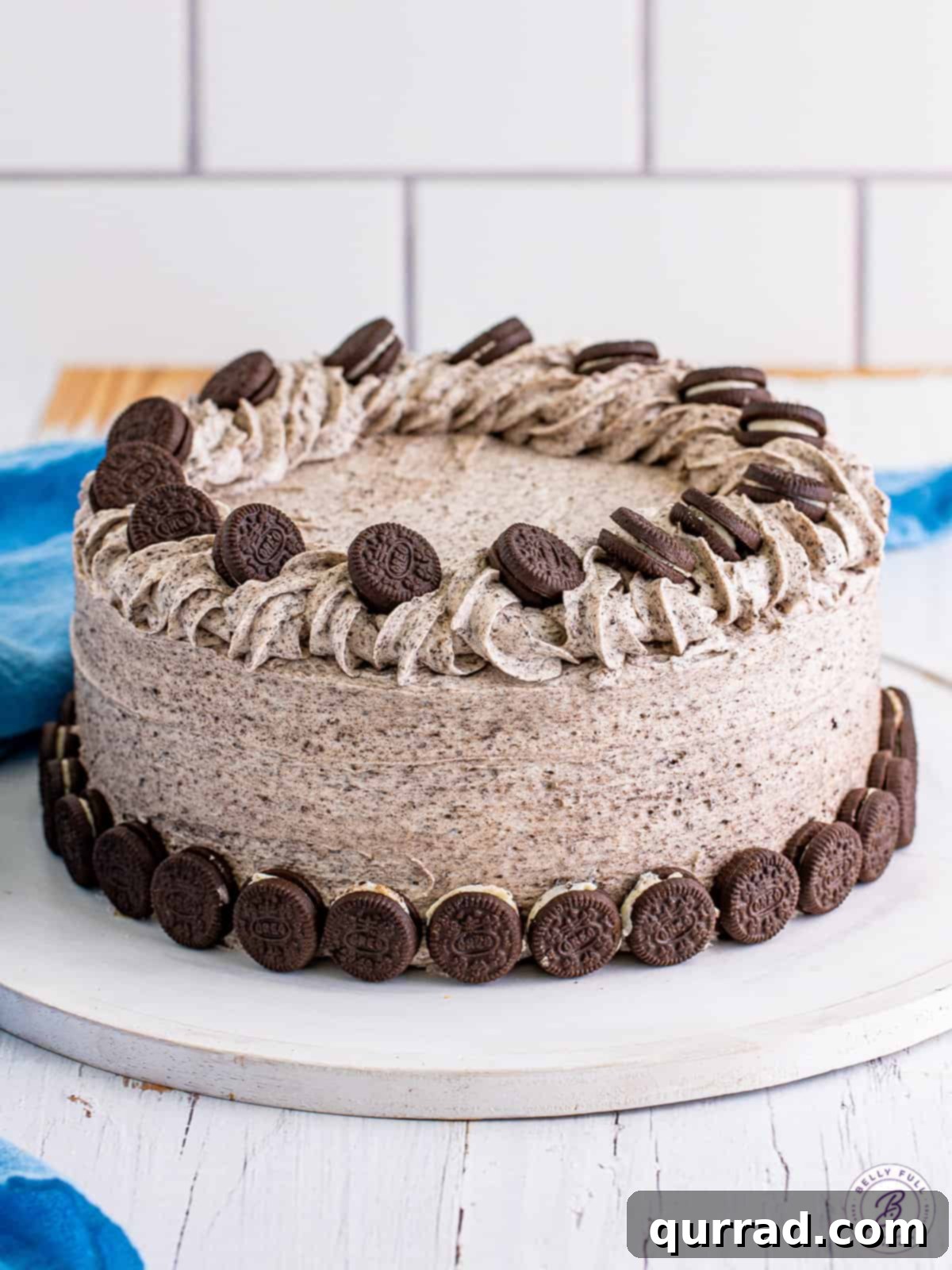 This easy Zebra Cake recipe features bold vanilla and chocolate stripes and is crowned with a luscious Cookies and Cream Frosting. A delectable zebra cake generously covered in a thick layer of speckled cookies and cream frosting, adorned with miniature Oreo cookies on top.