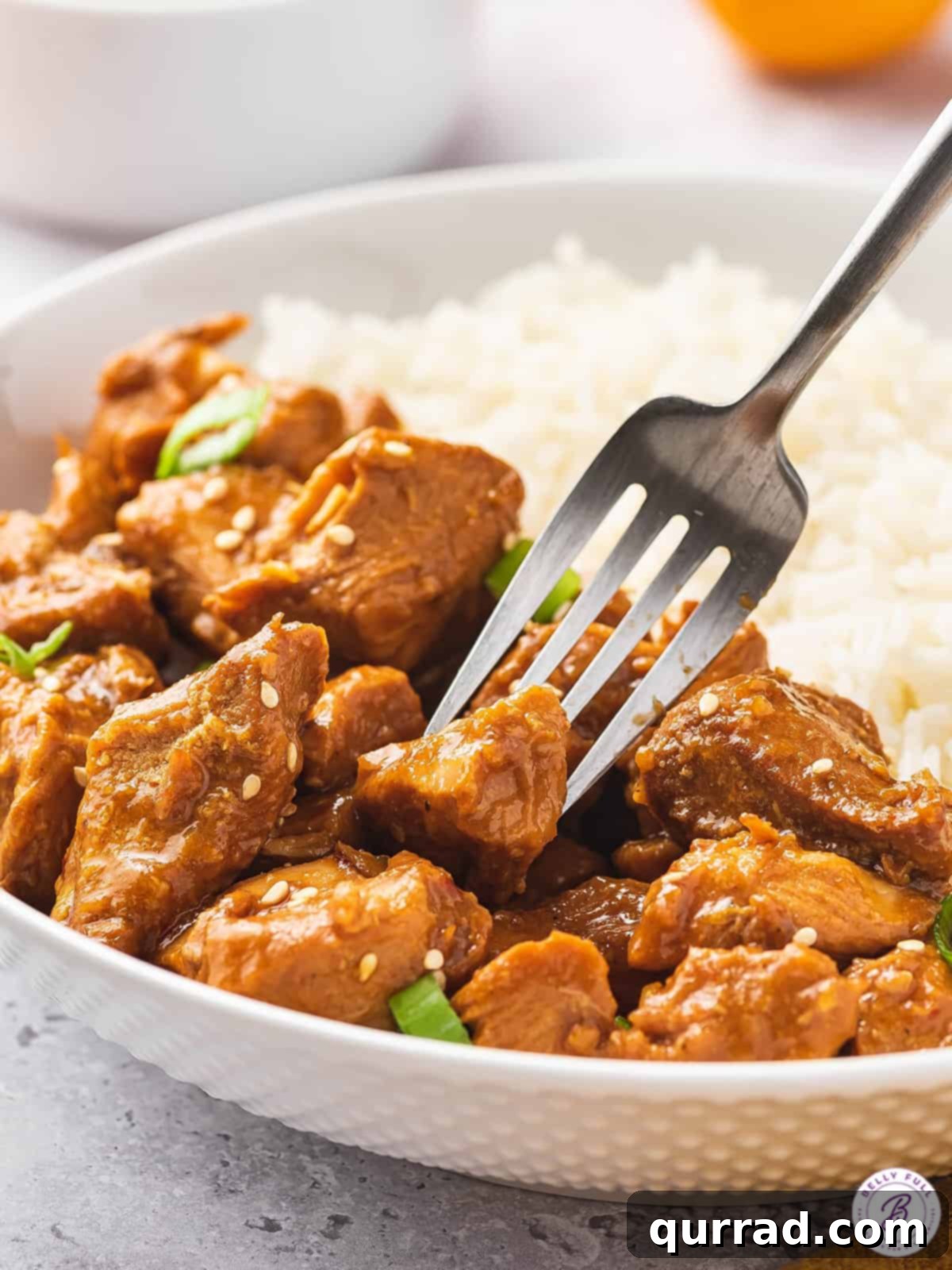 A fork stabbing a piece of crockpot orange chicken, showcasing its tender and juicy texture