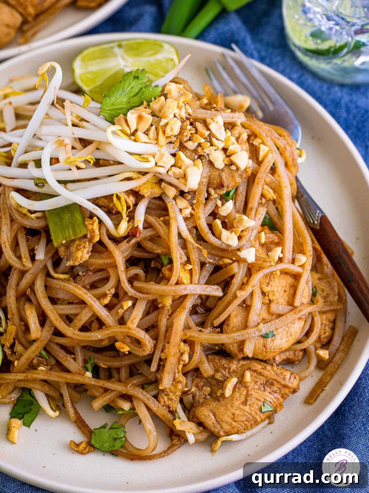 Master restaurant-quality Chicken Pad Thai at home with this authentic, easy-to-follow recipe, ready in just 45 minutes! Angled view of a beautifully presented plate of chicken Pad Thai, garnished with fresh lime, crushed peanuts, and cilantro.
