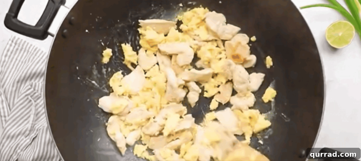 Chicken Pad Thai Perfection 7 Cooked chicken being returned to the wok, mixing with scrambled eggs and garlic before adding noodles and sauce.