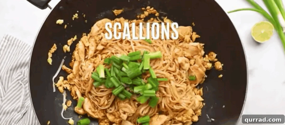 Chicken Pad Thai Perfection 8 Fresh scallions and bean sprouts being tossed into the Pad Thai in the wok during the final cooking stage.