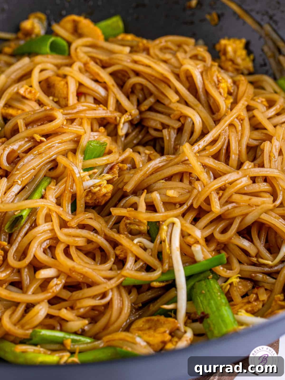 Experience the authentic textures and rich flavors of homemade Chicken Pad Thai, perfectly cooked in a wok. Close-up of freshly cooked Pad Thai in a large wok, showcasing the saucy noodles and vibrant ingredients.
