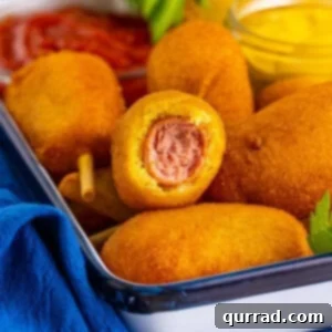 Finished mini corn dogs ready to serve, with a bite taken from one.