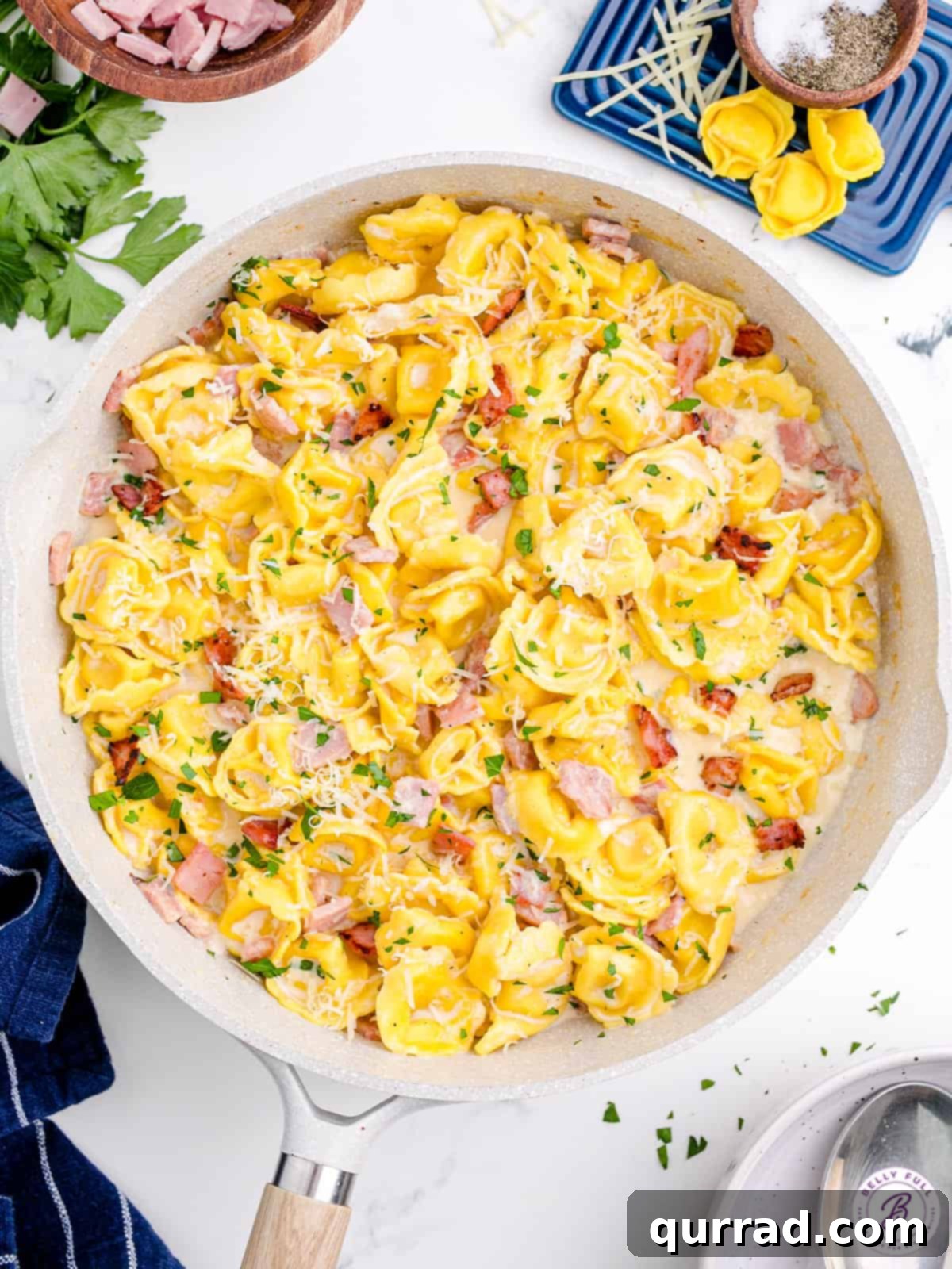 Overhead view of a bowl of Tortellini Alla Panna, garnished with fresh parsley and Parmesan