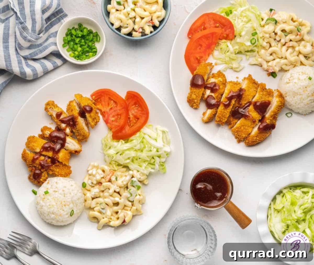 Panko-Crusted Chicken Katsu 9 Overhead view of two plates of Chicken Katsu, each with sliced chicken, tonkatsu sauce, shredded cabbage, rice, and tomatoes.