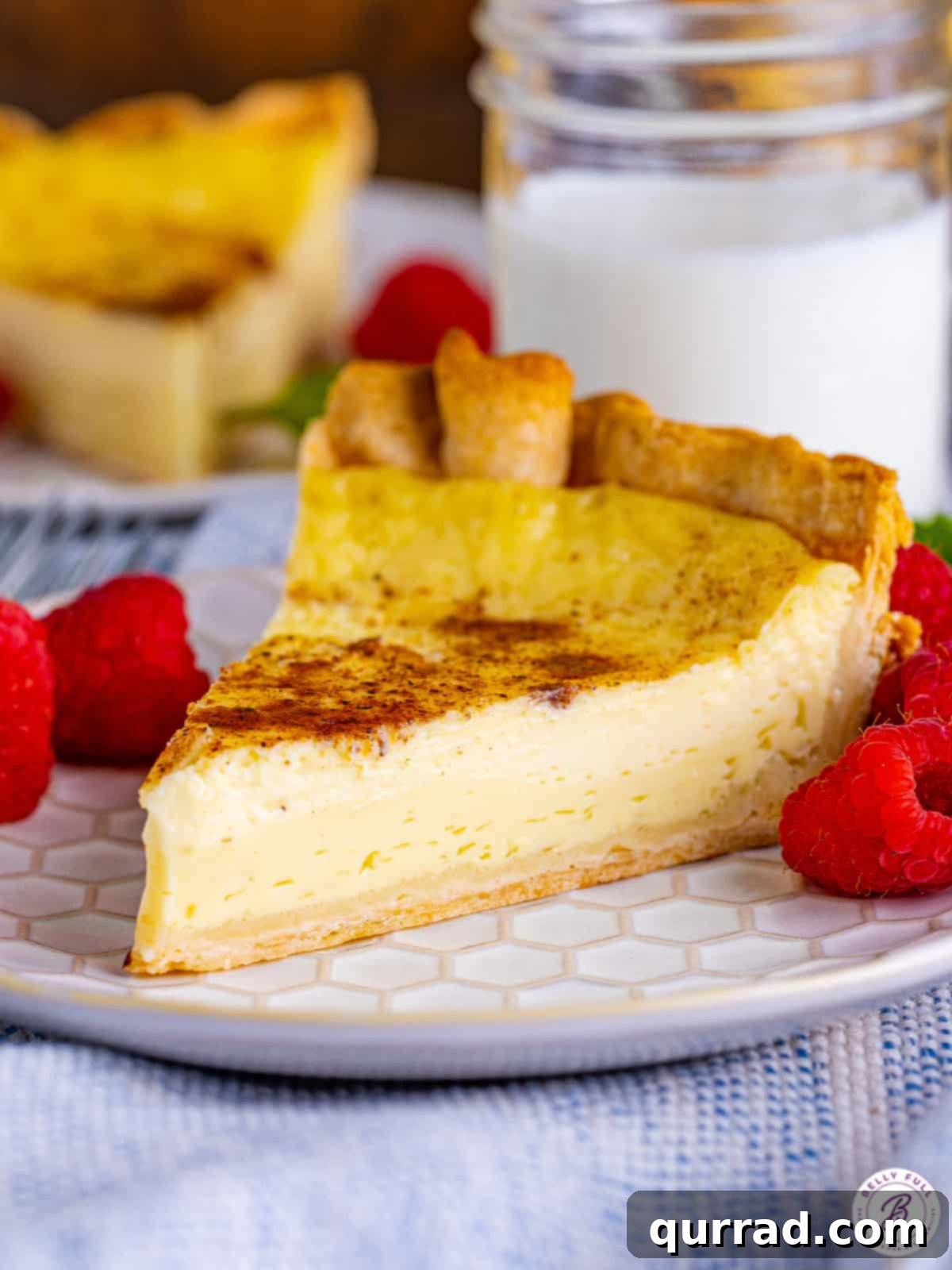 Experience the delight of this Easy Custard Pie, a classic dessert crafted with just 8 key ingredients. Its rich, creamy filling offers the perfect sweetness, making it an irresistible treat. A perfectly sliced piece of creamy custard pie adorned with fresh red berries on a white plate, ready to be enjoyed.