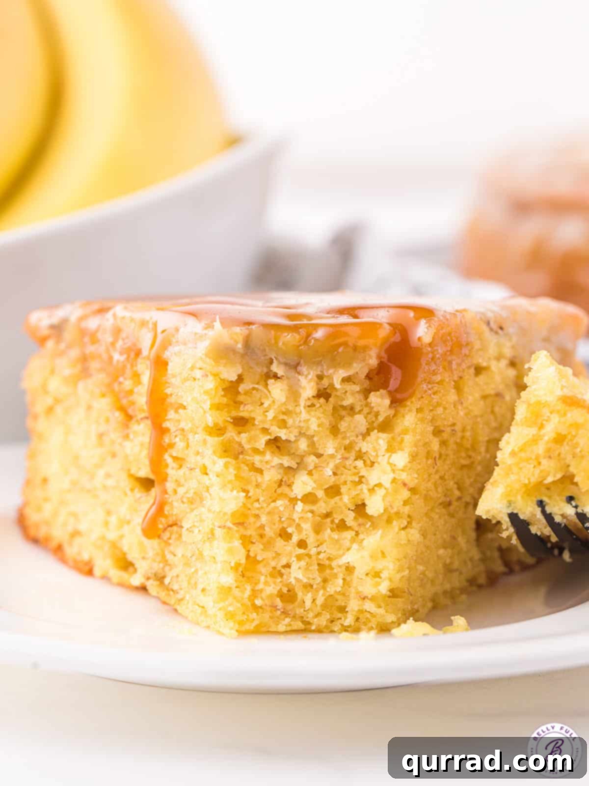 Golden Caramel Banana Flip 5 A perfectly sliced piece of Banana Upside Down Cake, showcasing the tender cake, the golden caramelized banana topping, and a hint of steam rising, suggesting it's freshly served and warm.