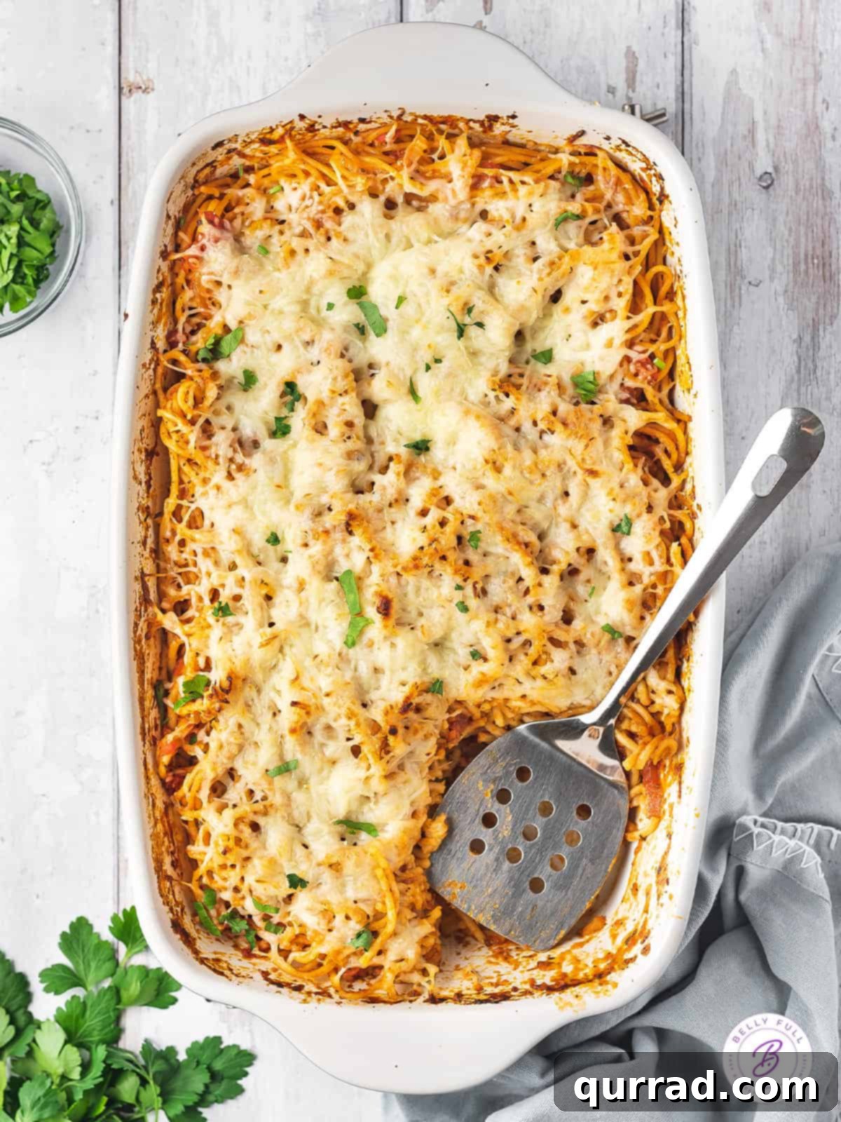 No pre-cooking needed! Just toss, add broth, and bake for amazing baked spaghetti. Overhead view of a bubbling, cheesy spaghetti casserole fresh from the oven.