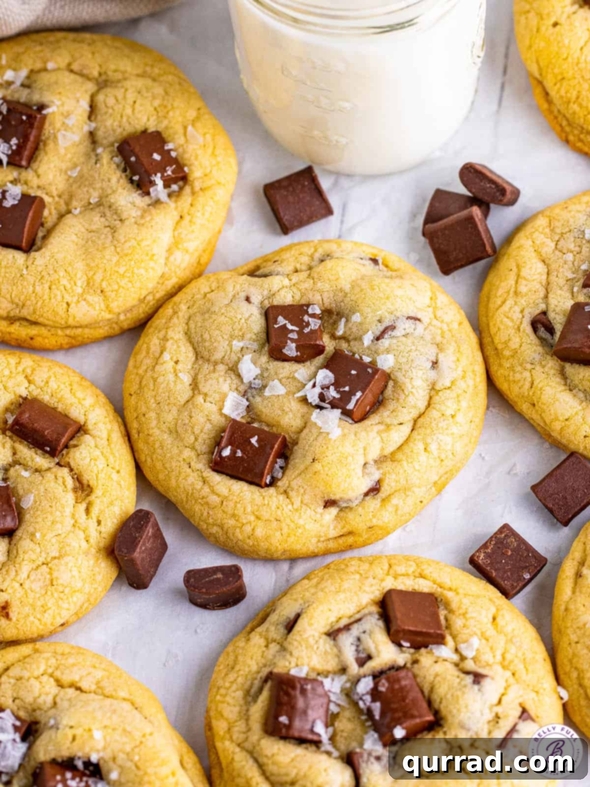 Experience bakery-quality Salted Chocolate Chunk Cookies, large, soft, and chocolatey, ready in under 30 minutes! An overhead view of several large, soft, and very chocolatey salted chocolate chunk cookies arranged on parchment paper