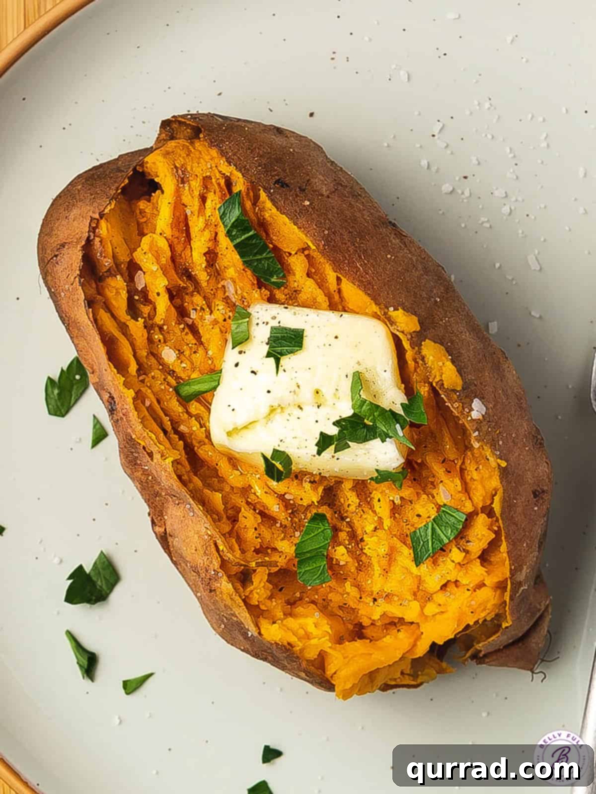 Close-up overhead shot of a freshly baked sweet potato with a melting pat of butter, ready to be enjoyed.