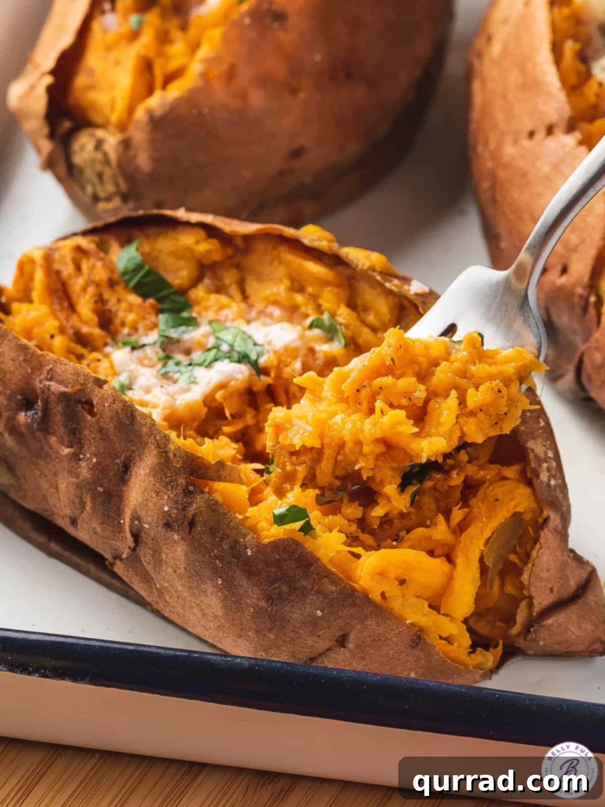 A fork piercing into a fluffy, air fryer baked sweet potato, showing its tender interior.