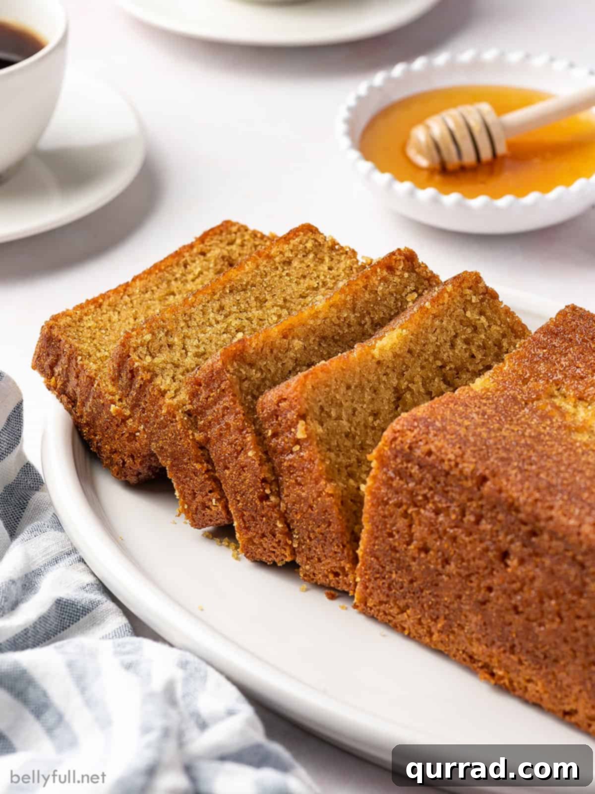Discover the ultimate Moist, sweet, and subtly flavored Honey Cake – a traditional Rosh Hashanah dessert made with only 11 simple ingredients and prepared in under an hour. A perfect treat for any time of the year! An inviting angled view of a half-sliced loaf of honey cake, revealing its golden, moist interior and rustic exterior.