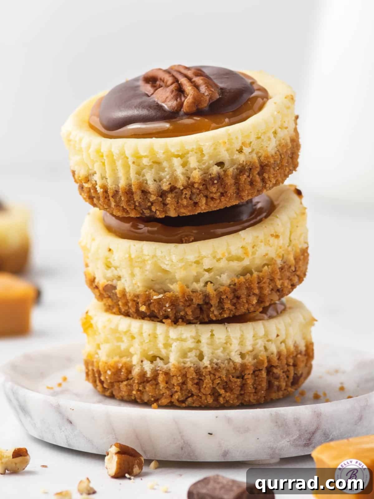 Topped with caramel, chocolate, and pecans these Mini Turtle Cheesecakes are a spin off the traditional candy. Easy to make & no water bath! Three turtle cheesecakes stacked on each other