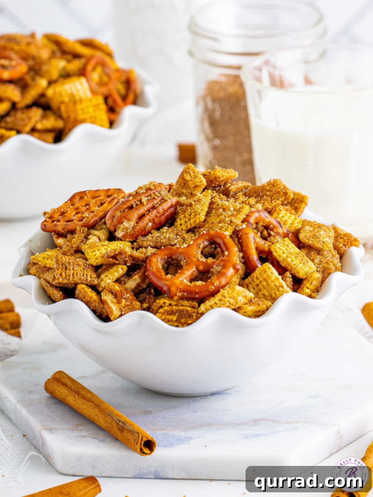 Cinnamon Sugar Chex Mix is an addictive party snack mix with a crunchy and sweet cinnamon coating. Great for gift-giving! A white bowl brimming with homemade cinnamon sugar Chex mix, ready to be enjoyed.