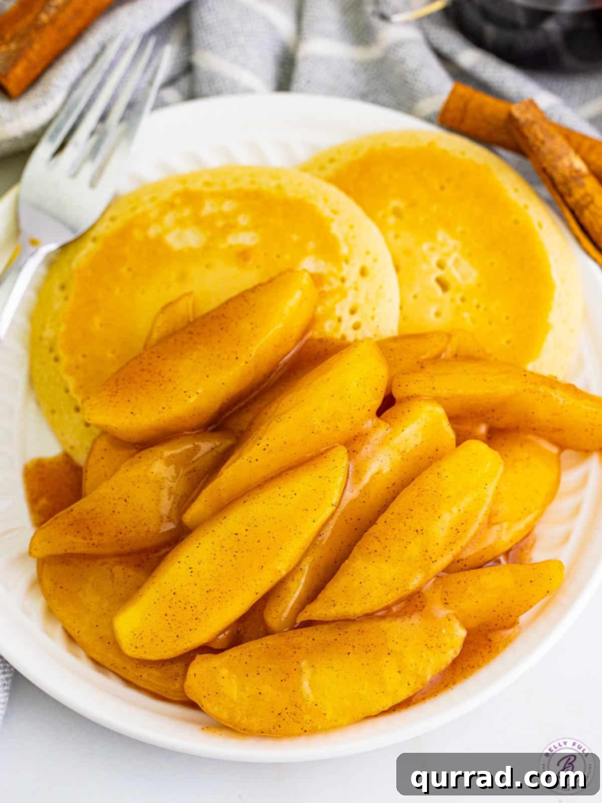 A plate of golden-brown fried apples generously piled next to a stack of fluffy pancakes, ready for a delicious breakfast.