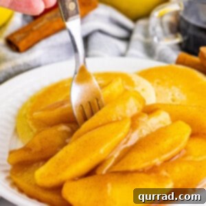 A fork diving into fried apples on a plate