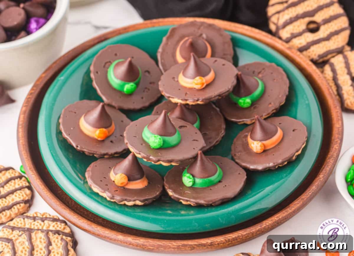 Overhead view of various colored witch hat cookies on a green plate, highlighting the different candy melt bands.
