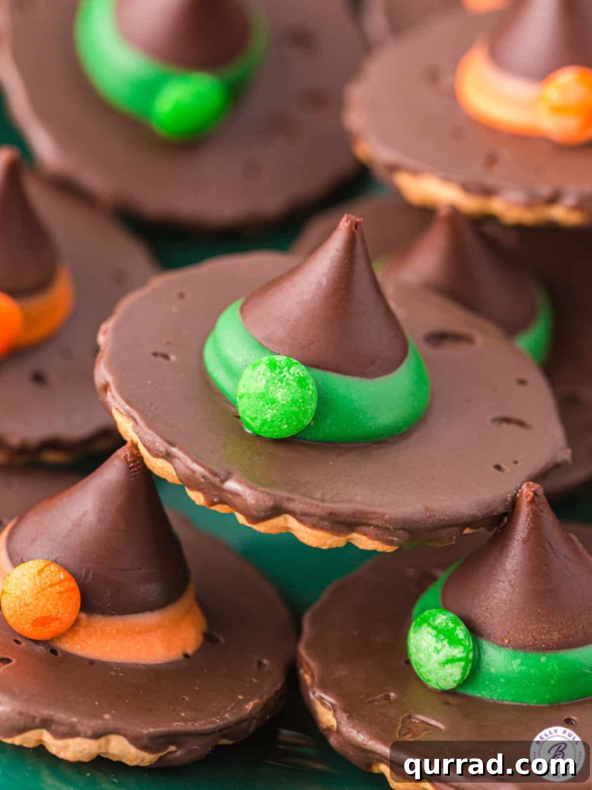 Close-up of vibrant Halloween witch hat cookies with orange and green candy melt bands.