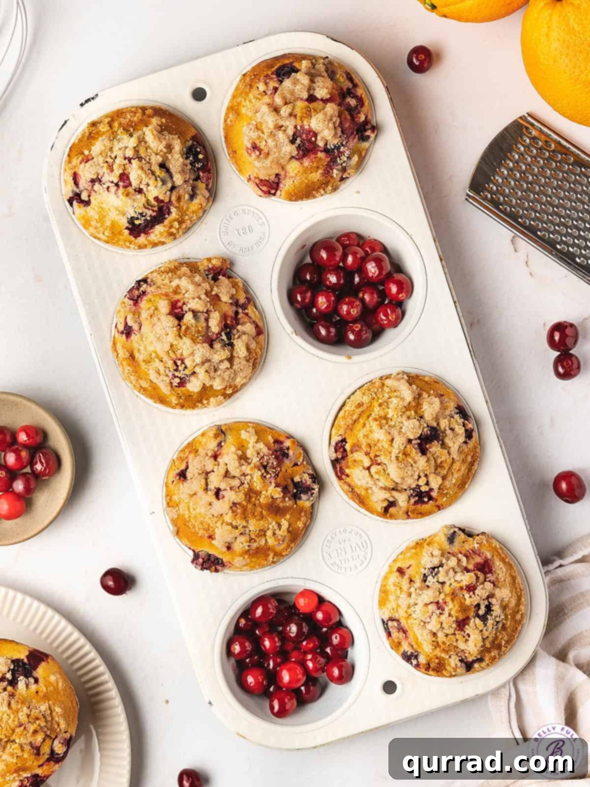 Made with tart cranberries, orange zest, and orange juice, these Cranberry Orange Muffins are bursting with flavor. Fluffy & moist! Overhead view of cranberry orange muffins in a muffin pan