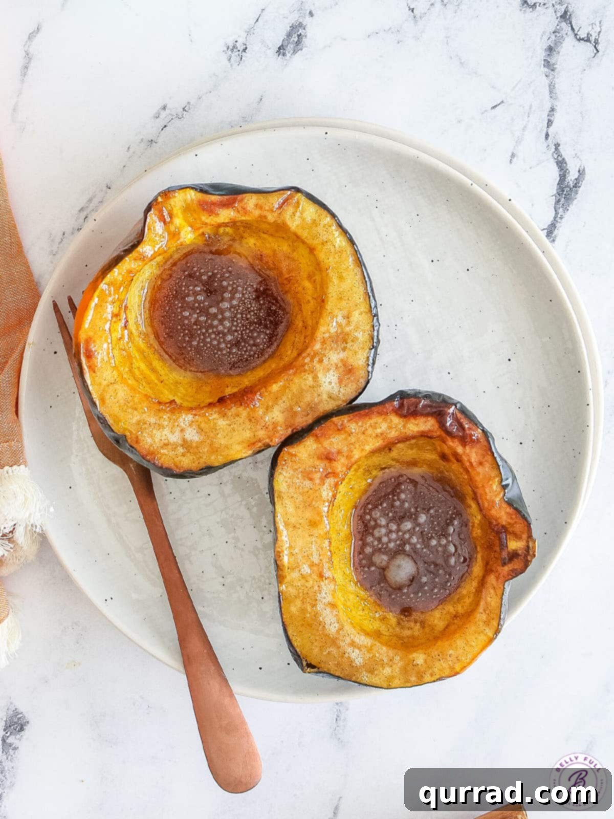 With just 4 ingredients, this Air Fryer Acorn Squash recipe turns squash into a flavorful, healthy side dish. Ready in just 30 minutes! Overhead view of two halves of an acorn squash, showing the distinct ridges and smooth skin before preparation.